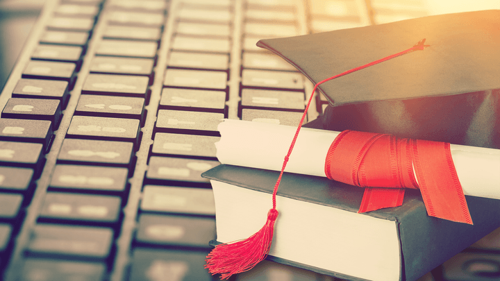 books, diploma and cap on a keyboard