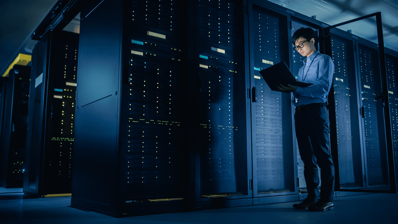 man holding laptop standing in control room representing how to get a data center technician job
