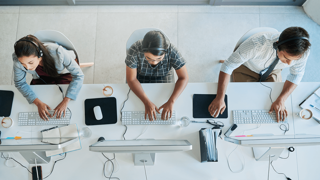 people sitting at computer workstations in row